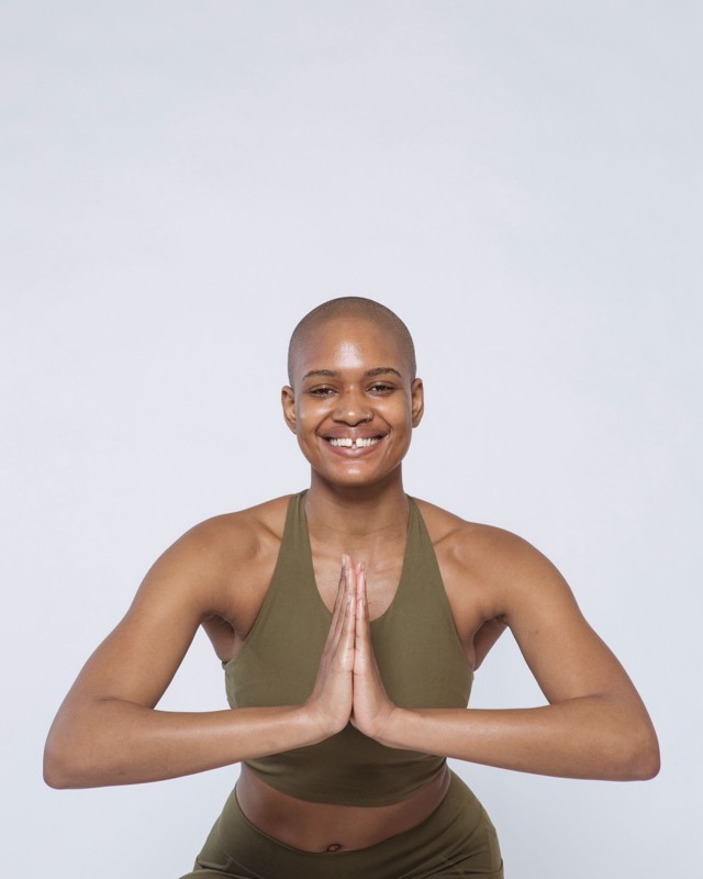 Amara, smiling, hands together, in an olive training set