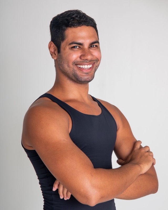 Karim, smiling, arms crossed, in a black tank top